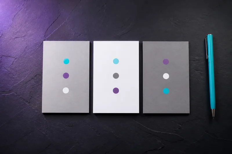 Neutral comparison cards on dark slate table with cyan pen